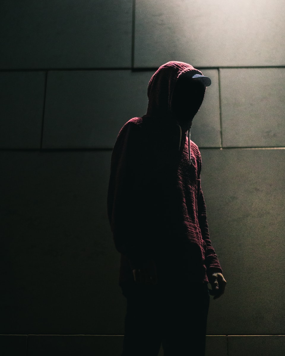person in red hoodie standing in front of gray brick wall