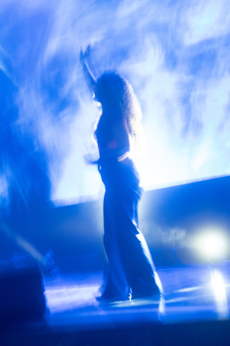 a woman standing on a stage with her arms in the air
