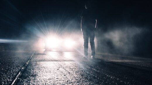 man standing in front of lighted car