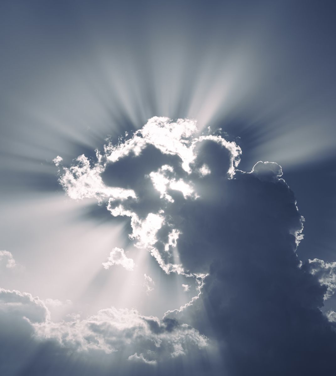 Sun rays burst through dynamic clouds creating a dramatic sky scene.